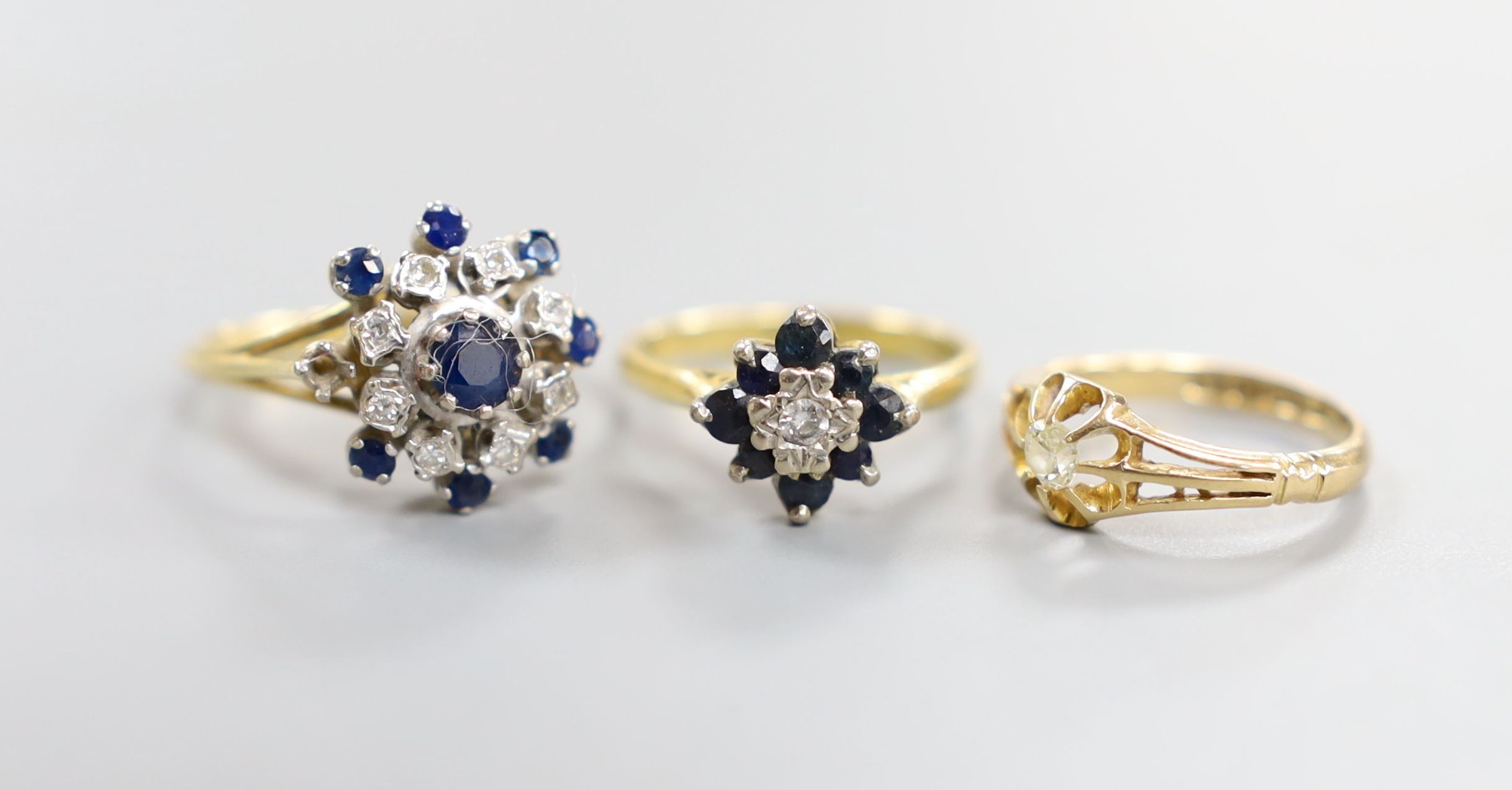 A George V 18ct gold and claw set solitaire diamond ring, size G/H and two later 18ct gold and gem set dress rings, gross 10.8 grams.